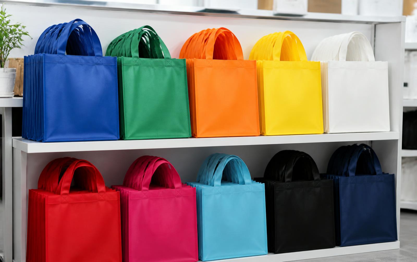 Stacks of colourful non-woven carry bags on retail shelving